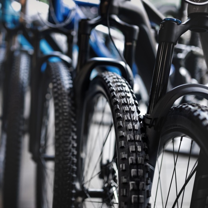 Eine Reihe von Mountainbikes mit auffälligen Reifen und blauen Rahmen steht auf einem Holzfußboden, präsentiert stolz ihre Räder und Federungen, während sie Teil einer neuen europäischen Business-Plattform für die Fahrradwirtschaft in Köln sind.